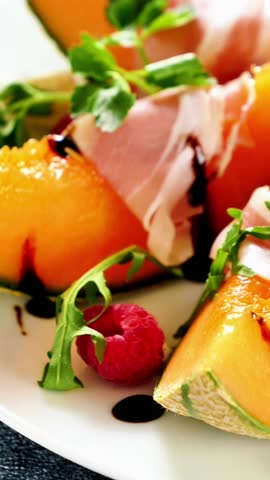 slices of melon with prosciutto ham and berries fruits