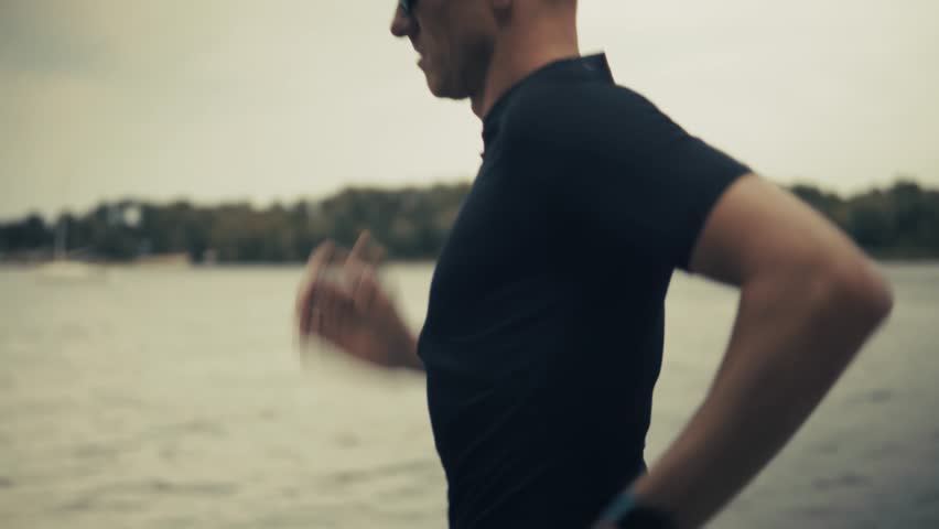 Professional Runner Training For Running Workout Along City Embankment, Active Runner Training Session During Running Workout Near River, Daily Exercise Routine, Runner Training Performance For Running Workout On Urban Path, Athletic Lifestyle, Physical Endurance, Summer Exercise, Outdoor Activity, Marathon Preparation, Healthy Exercise, Morning Jogging