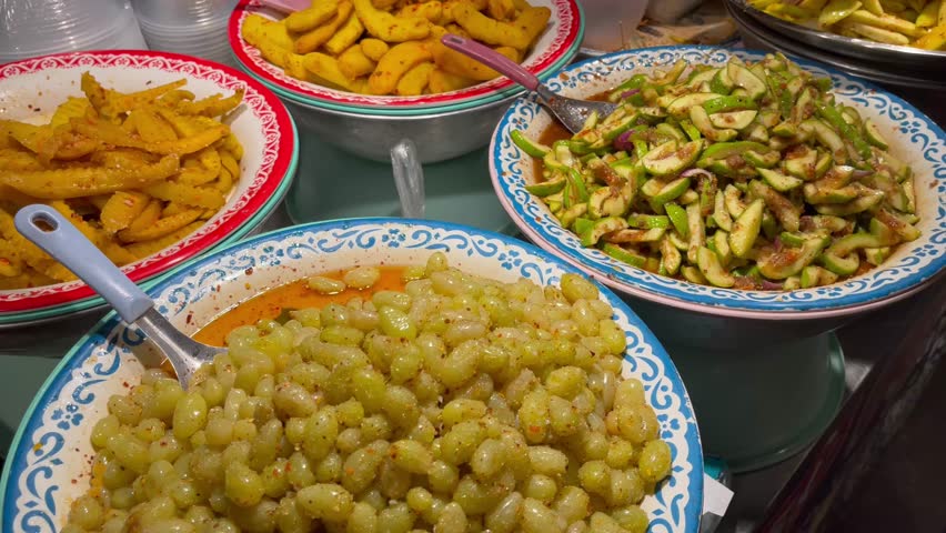Colorful Thai street food stall preparing spicy fruit salads with mango, guava, and tropical fruits, mixed fresh by hand at a local market in Thailand