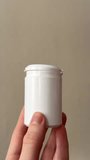 Hand holding a blank cosmetic bottle with pump dispenser against a neutral background. Minimal skincare packaging mockup suitable for branding presentation - Powered by Shutterstock - Get 15% off with code: PIKWIZARD15