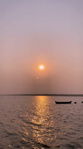 Golden hour reflections on water with a silhouette of a small wooden boat.