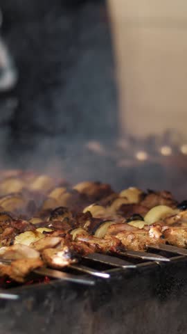 Grilled kebab cooking on metal skewer closeup. Roasted meat cooked at barbecue. BBQ fresh beef meat chop slices. Traditional eastern dish, shish kebab. Grill on charcoal and flame, picnic, street food