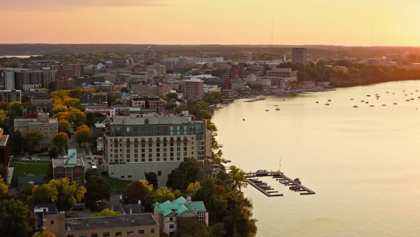 Madison, Wisconsin skyline at sunset with glowing city lights along the lakefront, capturing urban beauty and tranquil waters in golden light.