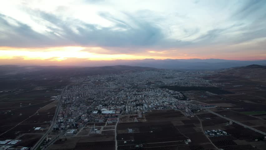 Breathtaking Aerial Sunset Panorama of Kilis Cityscape Surrounded by Agricultural Plains and Distant Mountains in Türkiye