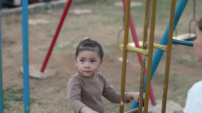 slow motion of cheerful child girl playing on double swing with her mother at outdoor playground