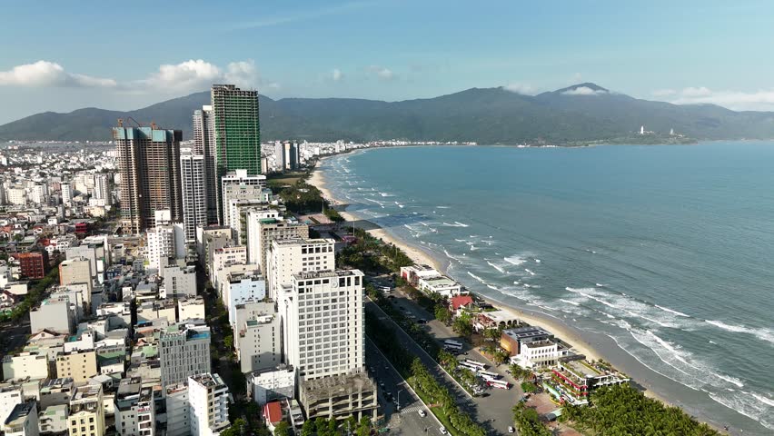 My Khe Beach, Da Nang, Vietnam – 4K aerial drone footage of tropical coastline, sandy beach, palm-lined coastline, ocean waves, and modern city skyline, costal roads, Son Tra Peninsula