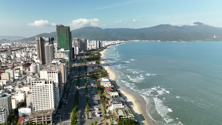 My Khe Beach, Da Nang, Vietnam – 4K aerial drone footage of tropical coastline, sandy beach, palm-lined coastline, ocean waves, and modern city skyline, costal roads, Son Tra Peninsula