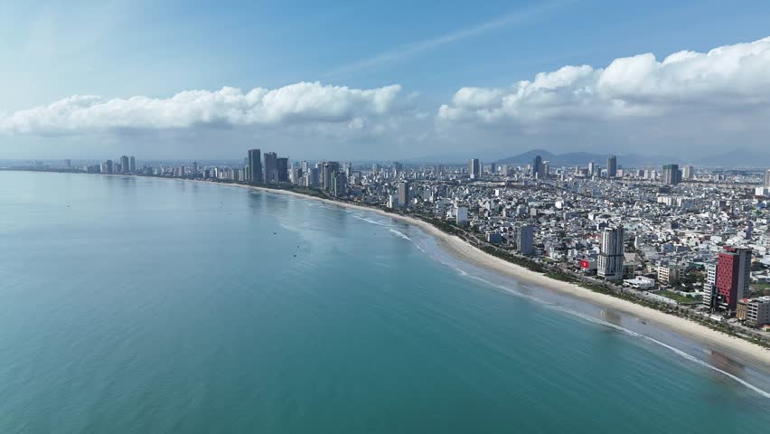 Da Nang, Vietnam – 4K aerial drone footage of Son Tra Beach, curved coastline, fishing boats with Vietnamese flag, fishing village, mountain backdrop and coastal city skyline in the morning