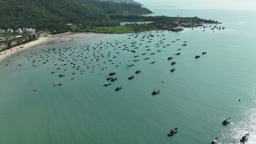 Son Tra Beach, Da Nang, Vietnam – 4K aerial drone footage of curved coastline, fishing boats with Vietnamese flag, fishing village, mountain backdrop and coastal city skyline in the morning