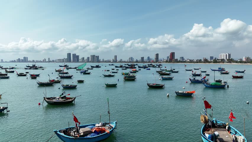 Son Tra Beach, Da Nang, Vietnam – 4K aerial drone footage of curved coastline, fishing boats with Vietnamese flag, fishing village, mountain backdrop and coastal city skyline in the morning