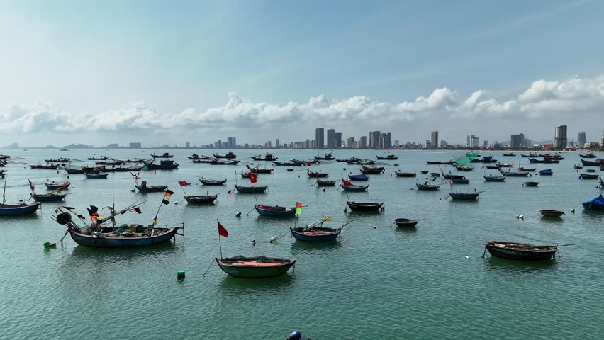 Son Tra Beach, Da Nang, Vietnam – 4K aerial drone footage of curved coastline, fishing boats with Vietnamese flag, fishing village, mountain backdrop and coastal city skyline in the morning