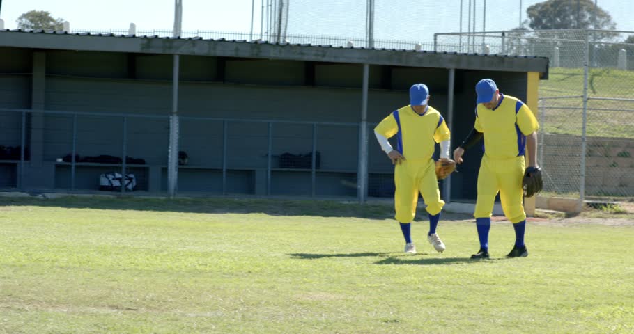 Arriving male players converging into huddle on outfield grass, catching ball in gloves. Athletics, teamwork, camaraderie, sportsmanship, outdoor, energetic, competitive