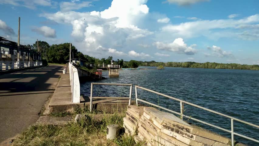 Water reservoir dam with blue sky and dramatic clouds, calm lake landscape in daylight, Sri Lanka