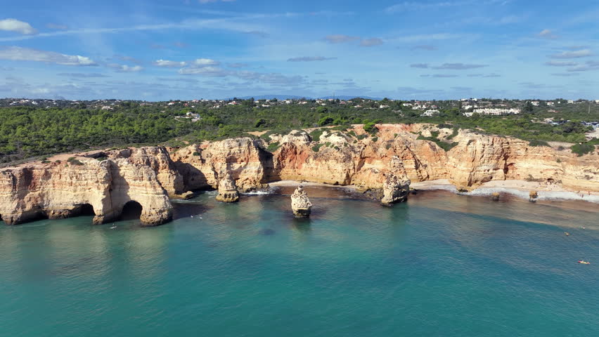 View of the European coastline at Praia da Marinha in the Algarve, Portugal, showing cliffs, rock formations and the Atlantic Ocean.