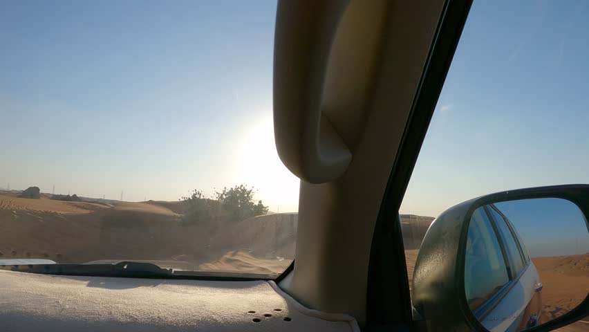 View through car window of sand dunes road in desert landscape with side mirror reflection, sunny day outdoors, point of view shot, concept of travel and road adventure.