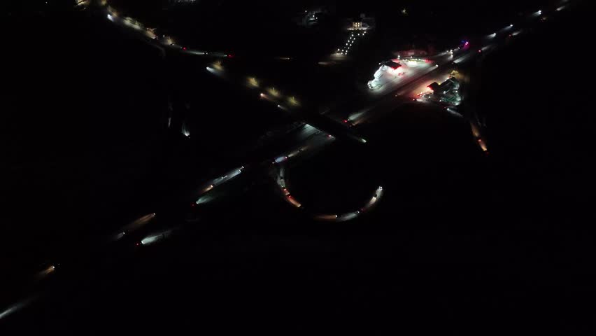 Static night aerial drone shot of highway junction with illuminated roads, 4K infrastructure scene.