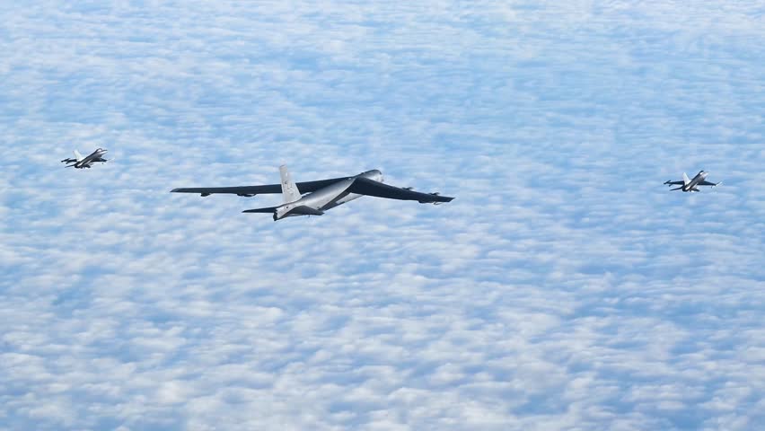 B-52 Stratofortress Escorted by F-16 Fighter Jets Over Expansive Cloud-Covered Skies During Mission.