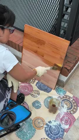 Young woman varnishing a small wooden plate outdoors