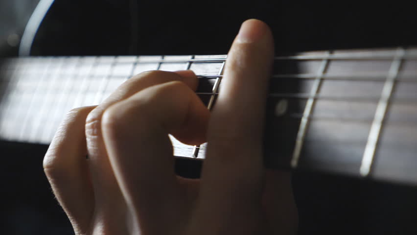 Close up arms of musician playing on electric guitar. Male fingers of guitarist strumming the strings. Hands of guy performing solo of rock music. Adult man plays on musical instrument. Dolly shot
