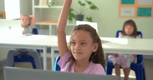Hearing teacher question, female child raising hand, typing on laptop in class while glancing up. Student, classroom, engagement, keyboard, smile, daylight, study - Powered by Shutterstock - Get 15% off with code: PIKWIZARD15