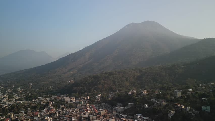 Aerial of Volcano San Pedro tilt down to town San Pedro La Laguna on Lake Atitlán Guatemala with hazy sky