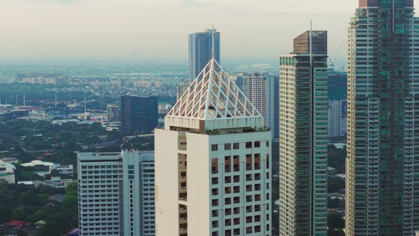 White geometric tower stands out among blue gray skyscrapers, Manila Philippines