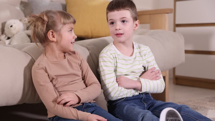 Little brother and sister spending time together on floor indoors