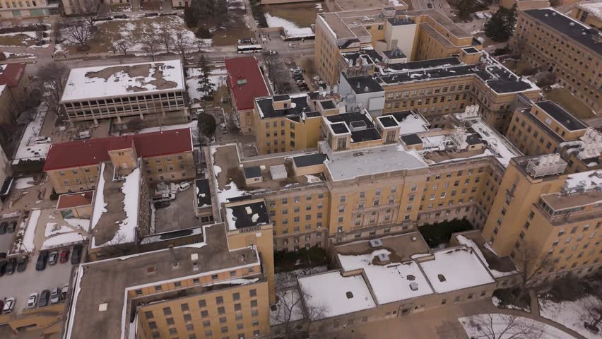 Smooth orbit aerial around academic buildings at the University of Wisconsin–Madison during peak snowfall in Madison.