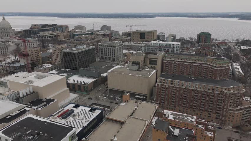 Aerial footage capturing icy shoreline and snow covered trees along Lake Mendota in Madison.