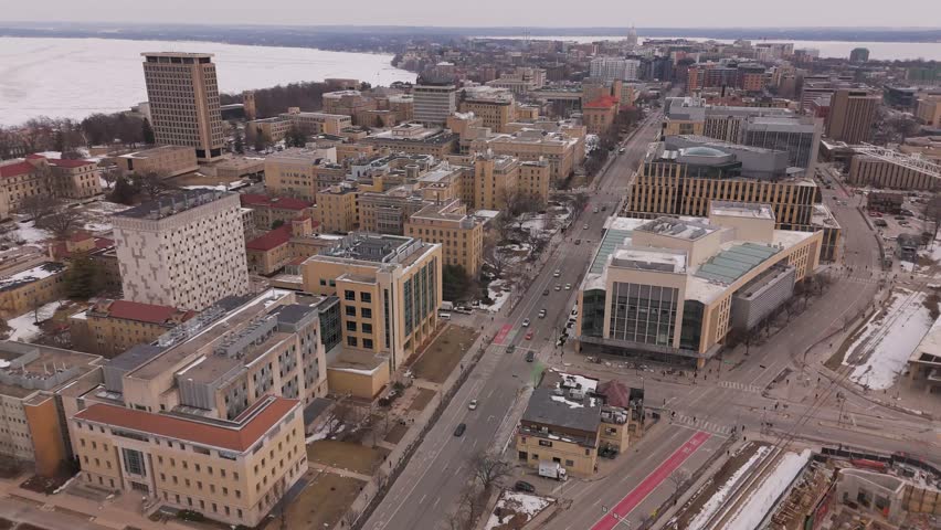 Wide aerial establishing shot of Madison surrounded by icy water and seasonal snowfall near Lake Mendota.