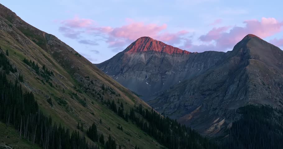 Alpine ridgeline and basin illuminated by soft pink sunset clouds in the San Juan Mountains, backdrop