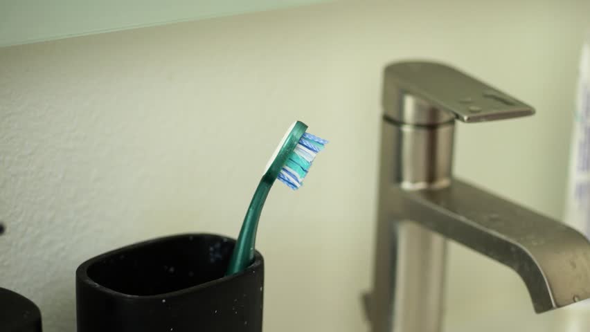 Closeup of a hand taking a toothbrush from its holder in the bathroom for morning dental routine