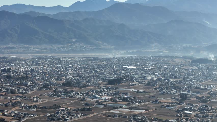 A city with a mountain in the background. The city is full of houses and buildings. The sky is cloudy and the sun is not visible