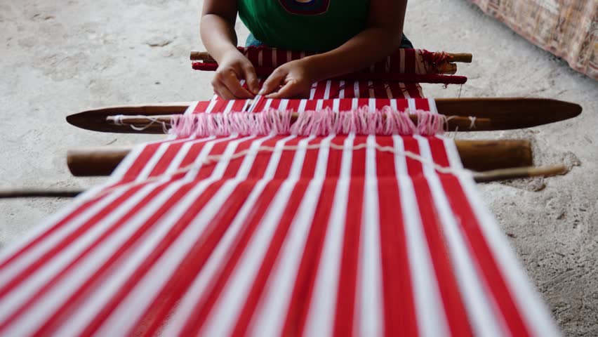 Traditional artisan weaving striped fabric on a backstrap loom
