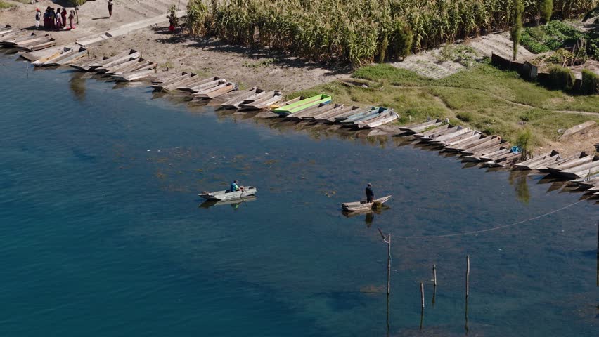 Two fishermen glide wooden canoes near shore on Lake Atitlan
