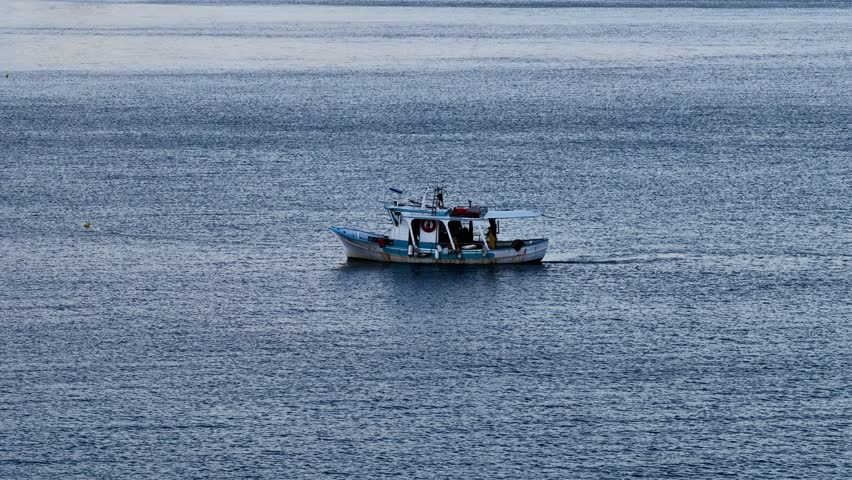 Traditional Greek fishing boat sailing in the deep blue open waters of the Ionian Sea off the coast of Corfu island, minimalist seascape with calm waves, Acharavi region, Greece, travel and maritime t