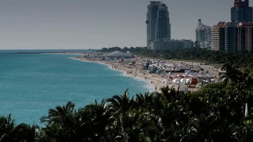 Scenic view of Miami Beach in Florida with turquoise waters, sandy shoreline, and towering high-rise buildings lining the vibrant coastal cityscape.