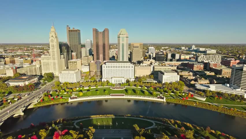 Aerial view of Columbus, Ohio skyline with the Scioto River on a sunny autumn day, showcasing vibrant fall colors and urban landscapes.