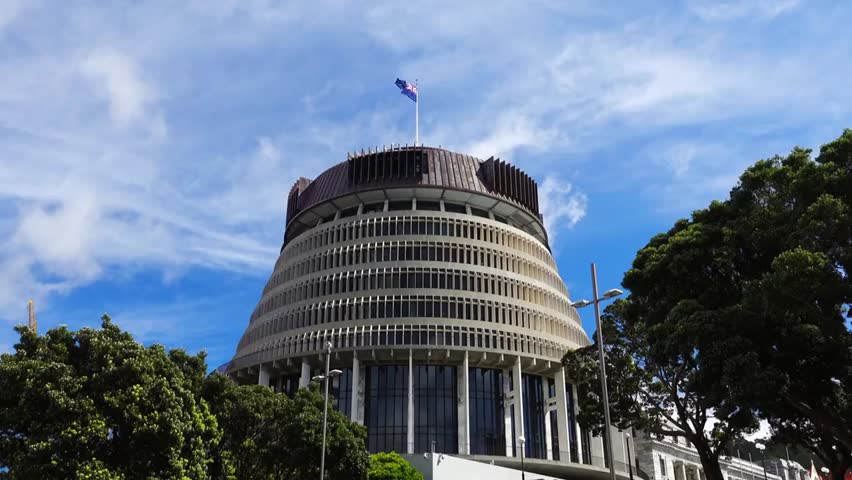 The iconic New Zealand Beehive Building stands under a bright blue sky with wispy white clouds, showcasing architecture and government heritage.
