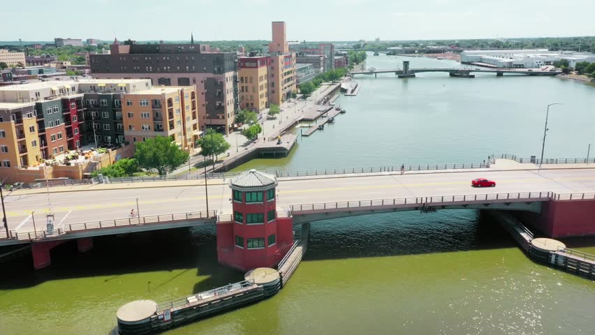 Aerial flyover  of Green Bay, showcasing Fox River waterfront, downtown skyline, residential neighborhoods, and scenic shoreline along Lake Michigan, panoramic Midwestern cityscape captured by drone in clear daylight.