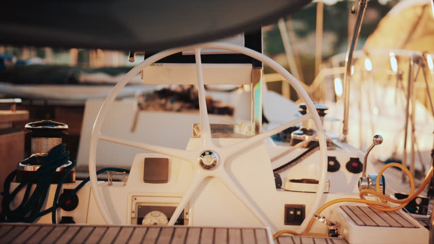 Close up view of a sailboat cockpit with ropes, steering wheel, and control levers