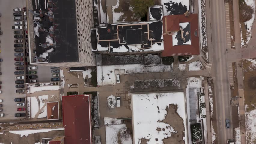 Cinematic pull-back drone reveal of Madison skyline with icy water in foreground near Lake Mendota.