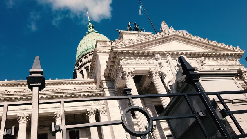 Low angle walk POV neoclassical facade and National Congress Palace in Buenos Aires, Argentina. Iconic landmark architecture under a blue sky
