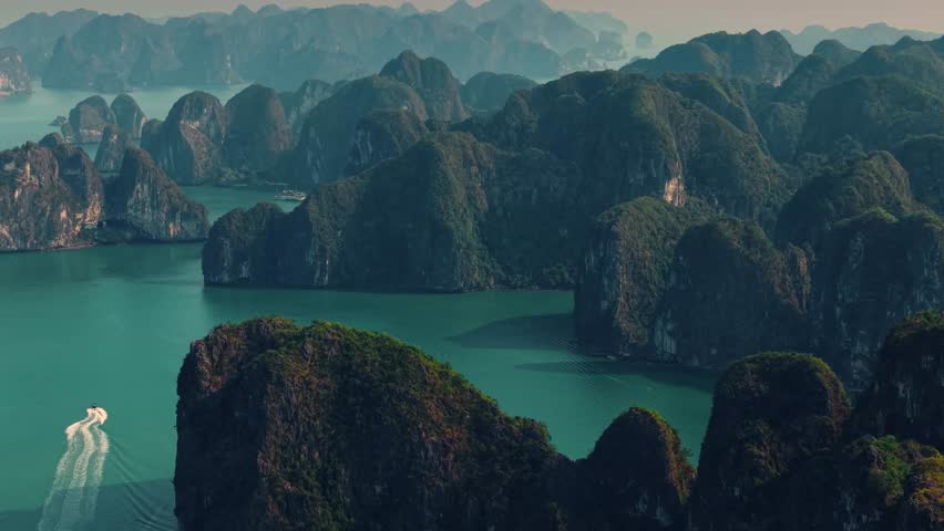 Aerial view of Halong bay with two speedboats conduct tour between limestone islets sunset time, tourist landmark of Vietnam.
