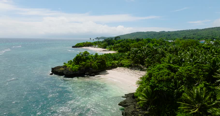 Corals and white beach with sun reflection in Carabao Island. San Jose. Romblon, Philippines.