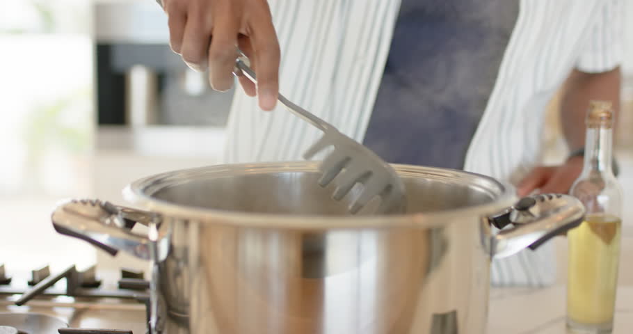 As gas burner is lighting, cook is stirring pot then is scooping spaghetti noodles for serving. Culinary, cooking, kitchen, gourmet, gastronomy, homecooking, modern