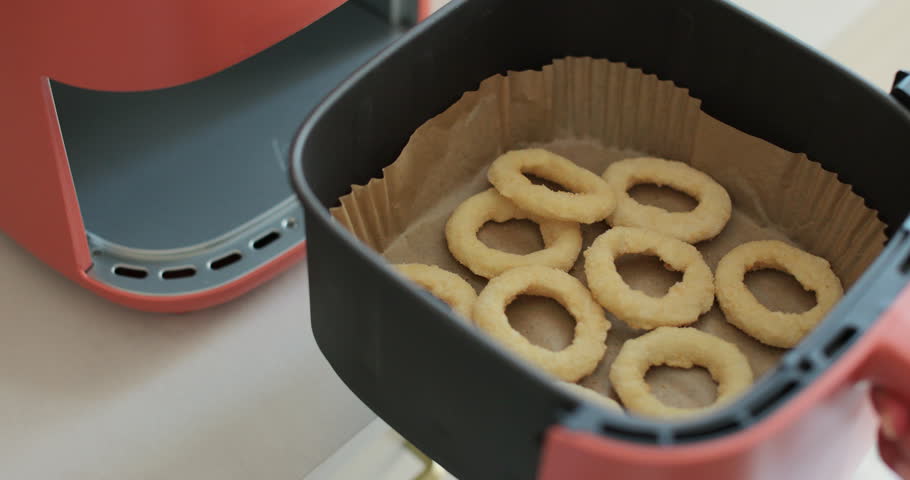 Close up of frozen onion rings in the air fryer. Healthy food for diet eating.