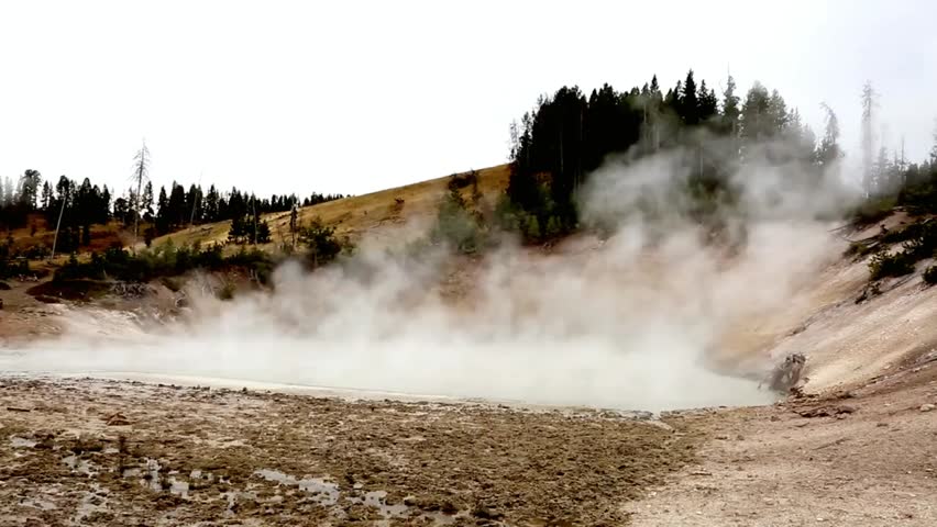 Scenic landscape with rising steam from geothermal features at Yellowstone National Park, Wyoming under open sky.