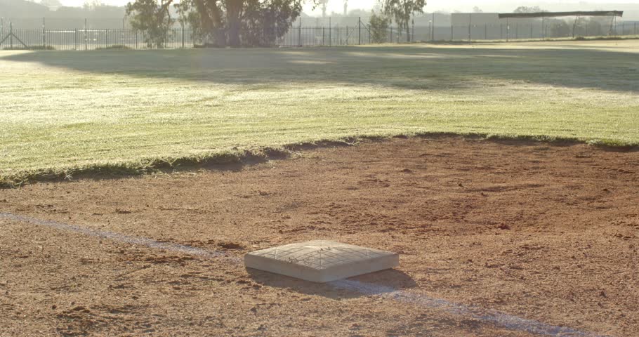 Sunrise prompting three male baseball players gathering on infield base, sharing bonding gestures. Athletics, teamwork, camaraderie, sportsmanship, outdoor, energetic, friendship