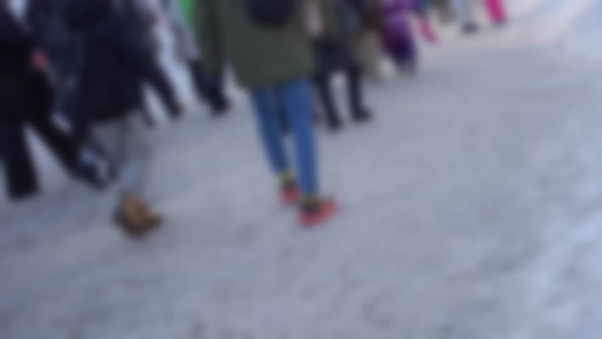 Low angle view of anonymous crowd walking on snowy road winter boots and feet